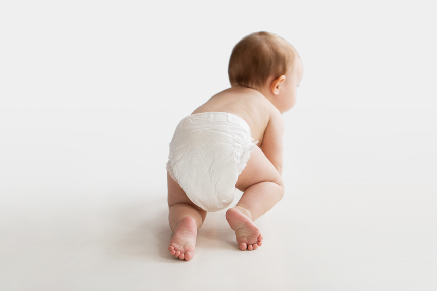 in diaper crawling on white floor